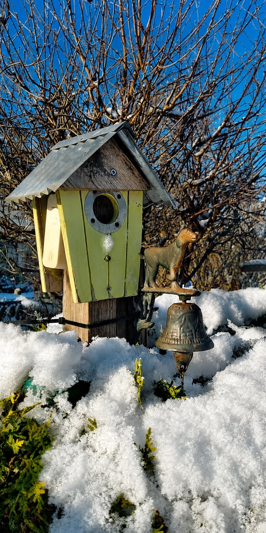 Vogelhaus mit Glöckchen im Schnee